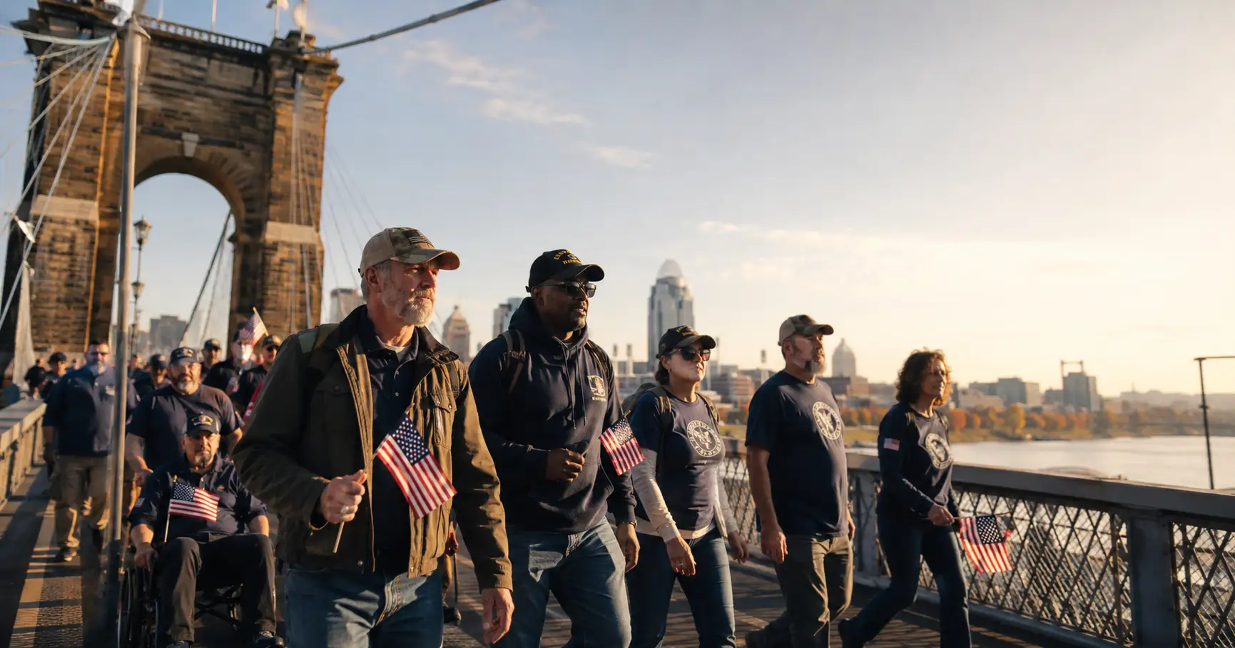 Veterans and supporters walking across the Roebling Bridge with the Cincinnati skyline behind them
